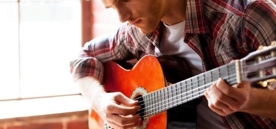 A handsome man playing an acoustic guitar