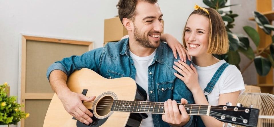 A happy couple playing an acoustic guitar together