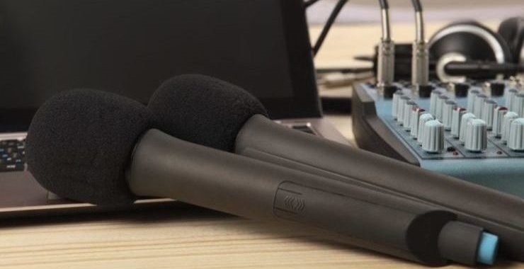 Two dynamic microphones side by side next to a laptop and recording equipment