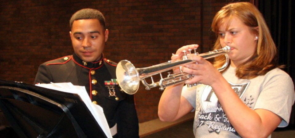 a girl playing the trumpet next to a guy