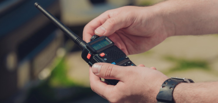 a hand changing the frequency of a Two-Way Radio