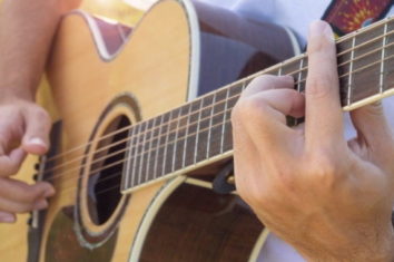 a man playing on an acoustic guitar that has a strap