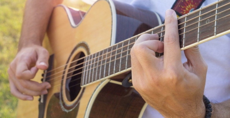 a man playing on an acoustic guitar that has a strap