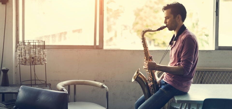 a man playing the saxophone sitting at a table