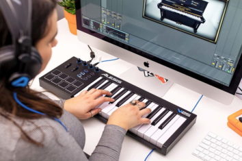 A woman using her midi keyboard with her computer