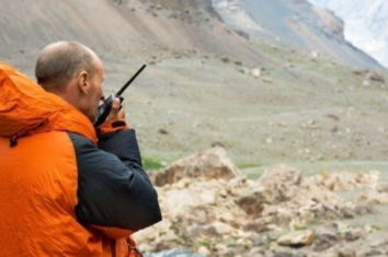 man out in the mountains using his two-way radio