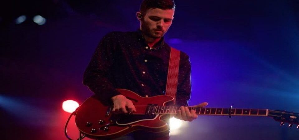 man playing red electric guitar